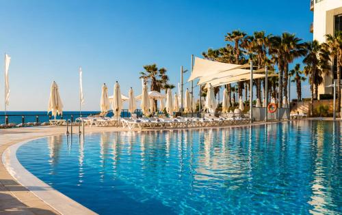 a swimming pool with umbrellas and chairs and the ocean at חדר על הים בהרצליה in Herzliya B