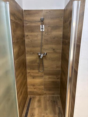 a shower stall with a wooden wall at Apartmán REBEKA in Holíč