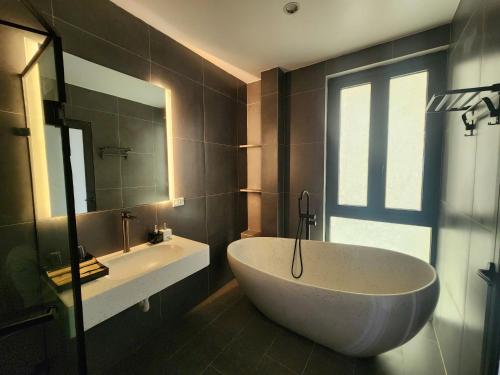 a bathroom with a large tub and a sink at DOS GATOS Hotel in Ðố Sơn