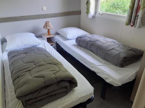 two twin beds in a room with a window at Mobil-home Moon River in Thiviers