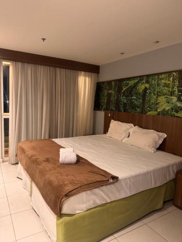 a bedroom with a large bed with a large painting on the wall at Flat Mercure Nova Iguaçu in Nova Iguaçu