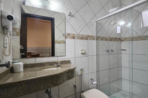 a bathroom with a sink and a mirror and a toilet at Esplendor Palace Hotel in Vitória da Conquista