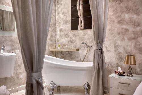 a bathroom with a tub and a sink and a shower curtain at Staytopus St Elizabeth - Modern Apartment - in Xewkija