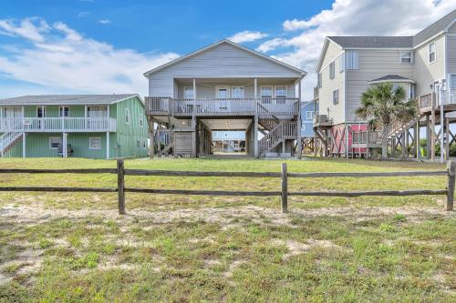 a house with a fence in front of a yard at No Worries in Oak Island