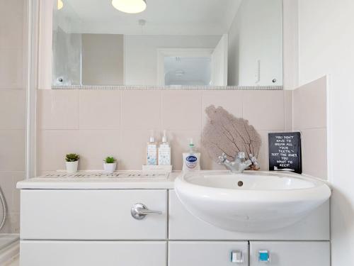 a white bathroom with a sink and a mirror at Shell Seekers - Selsey in Selsey