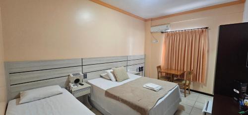 a hotel room with two beds and a chair at Esplendor Palace Hotel in Vitória da Conquista