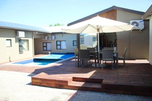 a patio with an umbrella and a table and chairs at A-Z Boutique Guesthouse in Windhoek