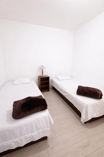 two beds in a room with white walls and wooden floors at Rinconcito de Paz en Xalapa in Xalapa