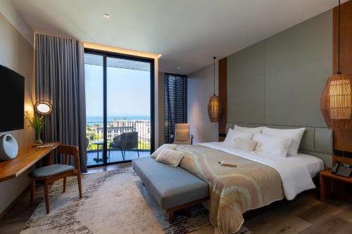 a bedroom with a bed and a desk and a large window at VARANA Krabi Hotel in Klong Muang Beach