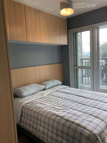 a bedroom with a bed with pillows and a window at Studio Praça Tatuapé in São Paulo