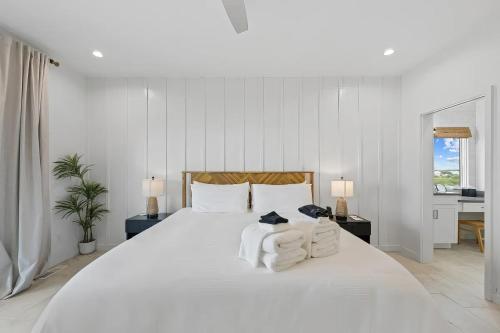 a white bedroom with a large white bed with towels at North Topsail Beach - Beachfront, Pool & HotTub in North Topsail Beach