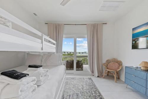 a white bedroom with a bed and a balcony at North Topsail Beach - Beachfront, Pool & HotTub in North Topsail Beach