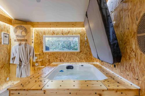 a jacuzzi tub in a wooden room with a window at L'Escale Sud Gironde - Séjour en amoureux avec jacuzzi privatif - Piscine - Massage Traiteur & Brunch possibles in Pompéjac