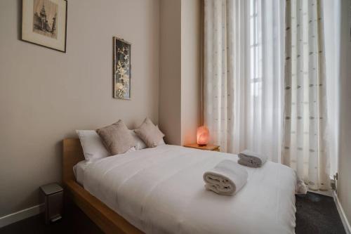 a bedroom with a bed with white sheets and a window at Luxurious Royal 2BR Apartment, Glasgow City Centre in Glasgow