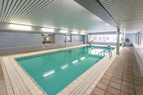 a large swimming pool in a building with a large pool at Studio Palace 217 in Middelkerke
