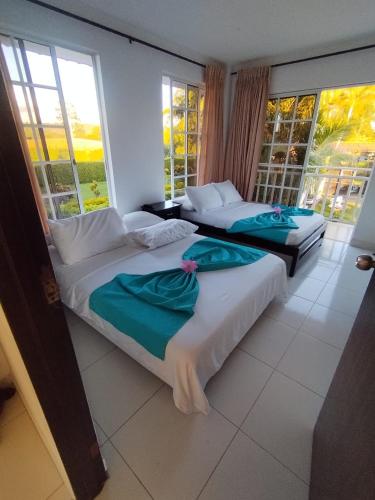 two beds in a room with two windows at Finca el Amanecer - 30P - Pool in Quimbaya