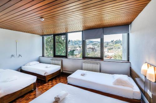 a room with two beds and two windows at HI São Pedro do Sul – Pousada de Juventude in Termas de Sao Pedro do Sul