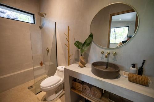 a bathroom with a sink and a toilet and a mirror at Garden Treehouse Ikhaya in Refundores