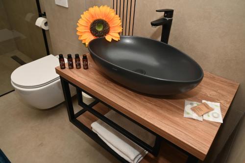 a black bathroom sink with a sunflower on a counter at Elysium2 in Banja Luka
