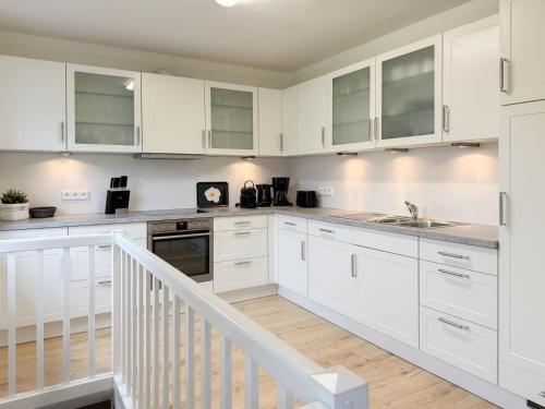 a white kitchen with white cabinets and a staircase at Cozy Home in Timmendorfer Strand