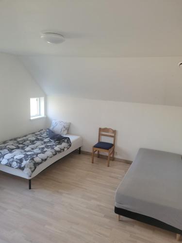 a bedroom with two beds and a chair at Yellow house in Skene