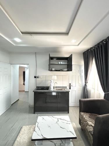 a living room with a couch and a kitchen at Saint Apartment by Bento in Gwarinpa