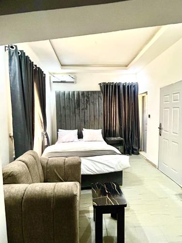 a bedroom with a bed and a couch in front of a bed at Saint Apartment by Bento in Gwarinpa