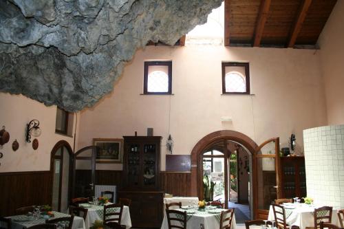a dining room with tables and chairs and a rock wall at Agriturismo La Grotta in Corbara