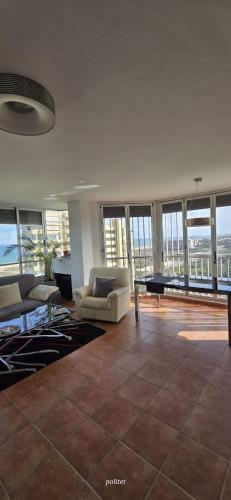 a living room with couches and a table and windows at Three Horizons Penthouse El Saler in Valencia