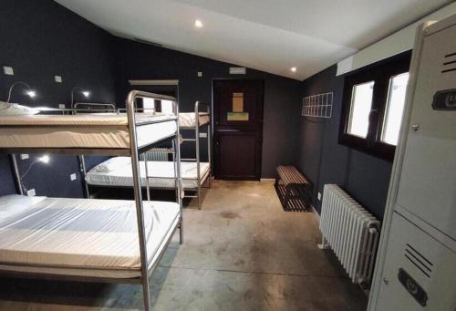 a room with three bunk beds and a kitchen at Casa Carmina Hostel in Muros de Nalón