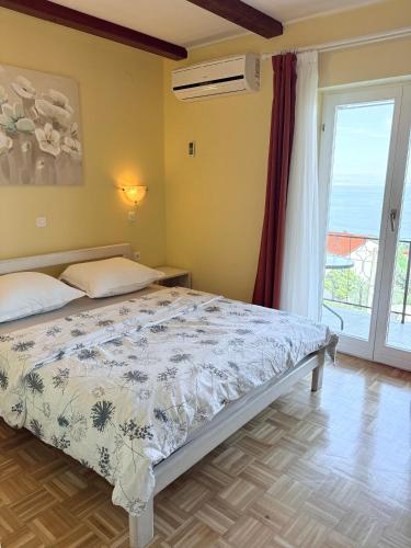 a bedroom with a bed and a large window at Guest house Ivo in Lovran