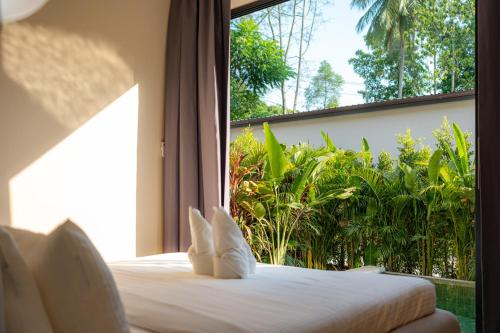 a bed in a room with a large window at Demaya Villa 5 in Ko Phangan