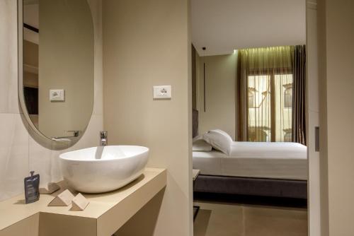 a bathroom with a sink and a bedroom with a bed at Fly Suite Rome Airport in Fiumicino