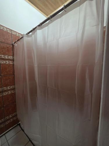 a shower with a white curtain in a bathroom at Volcano Hostal in Rivas