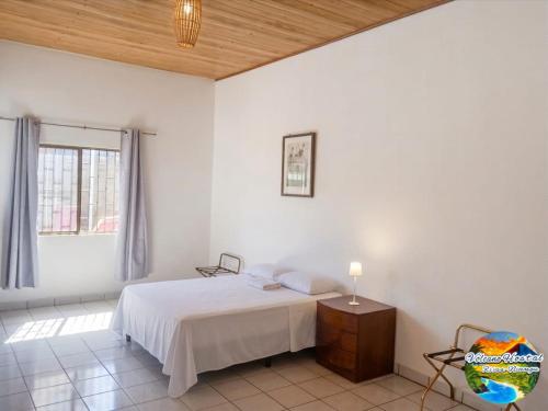 a white bedroom with a bed and a window at Volcano Hostal in Rivas