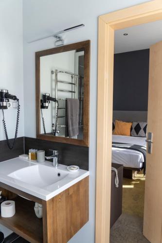 ein Badezimmer mit Waschbecken, Spiegel und Bett in der Unterkunft Hotel Kolumbs in Liepāja
