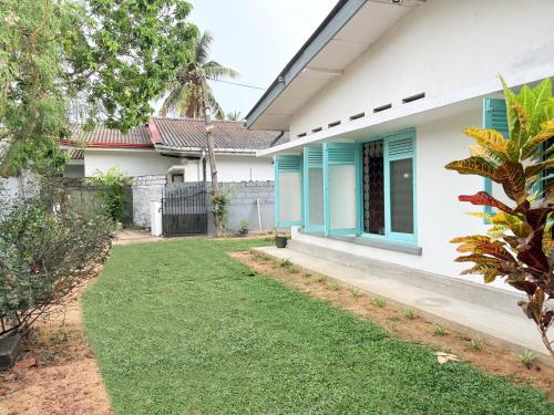 a house with blue windows and a yard at Achcha's Place in Negombo
