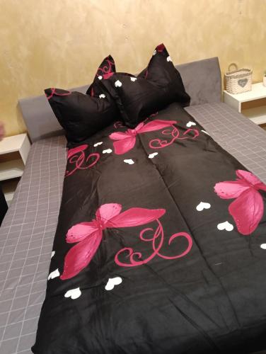 a bed with a black comforter with pink butterflies at casa lidia in Brăila