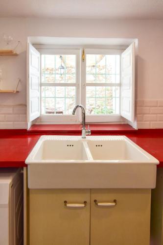 a kitchen with a white sink and two windows at La Calma de Vilo in Periana