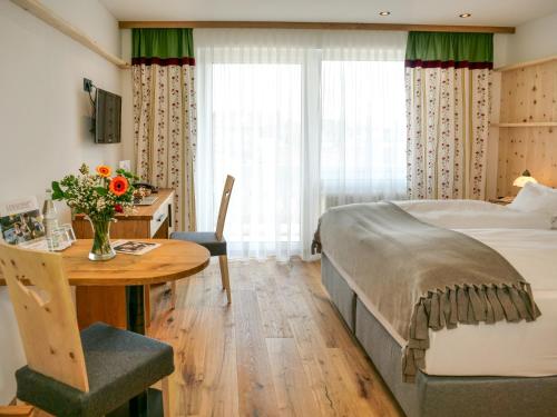 a hotel room with a bed and a desk and a table at Hotel LENAUHOF - nur 3 Minuten zur Rottal Terme - in Bad Birnbach