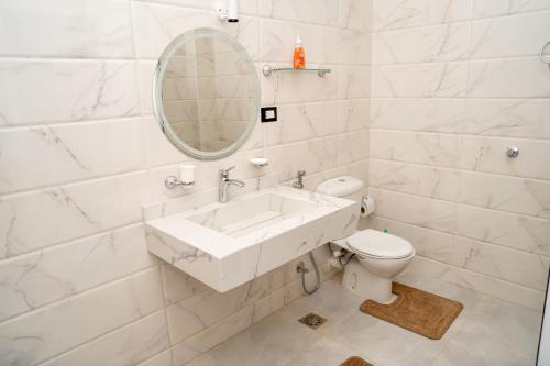 a white bathroom with a sink and a toilet at Azure Guest House in Luxor
