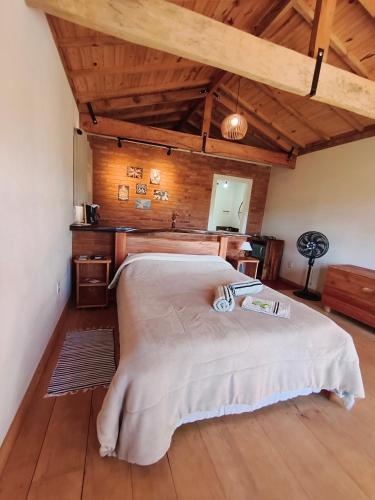 a bedroom with a large bed in a room with wooden ceilings at Chalé Das Quaresmeiras in Aiuruoca