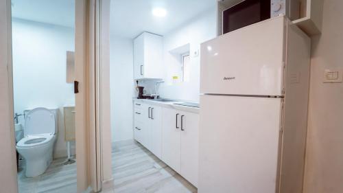 eine weiße Küche mit Toilette und Kühlschrank in der Unterkunft Cocoaloa in Armilla