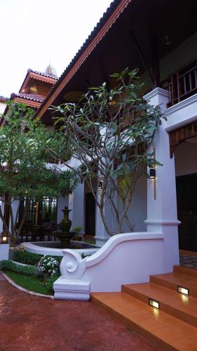 a white building with a tree in front of it at i Lanna House in Chiang Mai