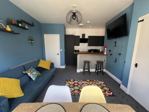 a living room with a blue couch and a kitchen at Full Apartment in the Heart of Margate in Margate