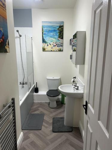 a white bathroom with a toilet and a sink at Full Apartment in the Heart of Margate in Margate