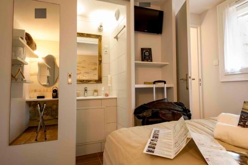 a bedroom with a bed and a sink and a mirror at Hotel Arc-En-Ciel Colmar Contact Hotel in Colmar