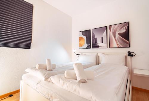 a bedroom with a white bed with four pictures on the wall at Bissone Campione Lake Pool & Relax in Bissone