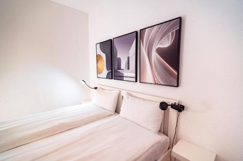 a bed in a room with three pictures on the wall at Bissone Campione Lake Pool & Relax in Bissone