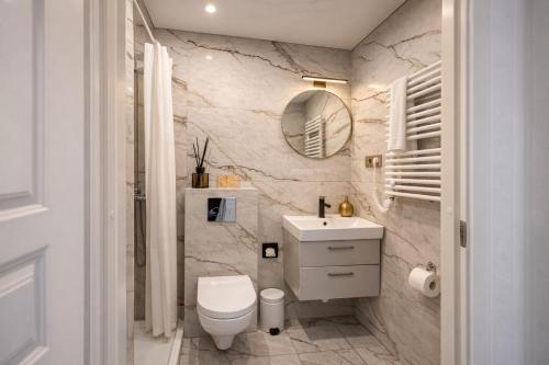 a bathroom with a white toilet and a sink at MMA Apartament with Private Garden & Terrace in Klaipėda